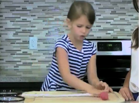 Kid demonstrating how to twist two colours of clay together