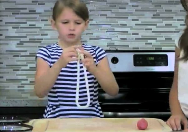 Kid demonstrating how to make the clay into a long loop