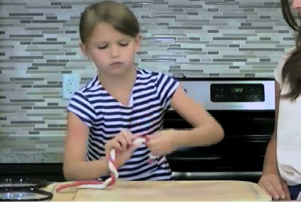 Kid demonstrating how to twist three colours of clay together