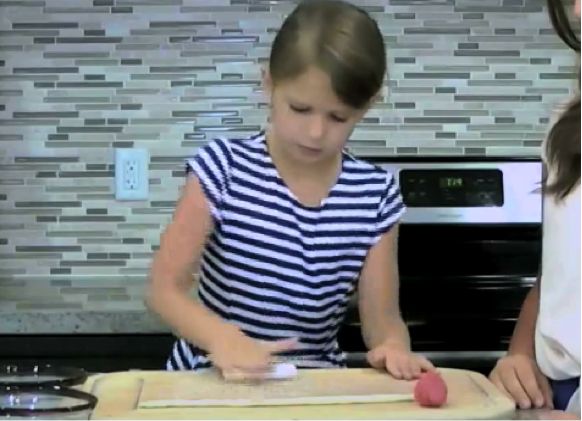 Kid demonstrating how to roll the polymer clay